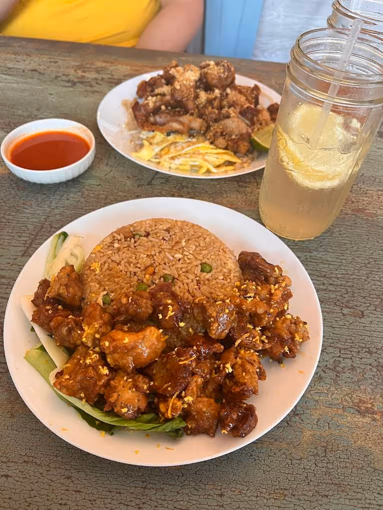 A plate of chicken with rice and a glass of lemonade.