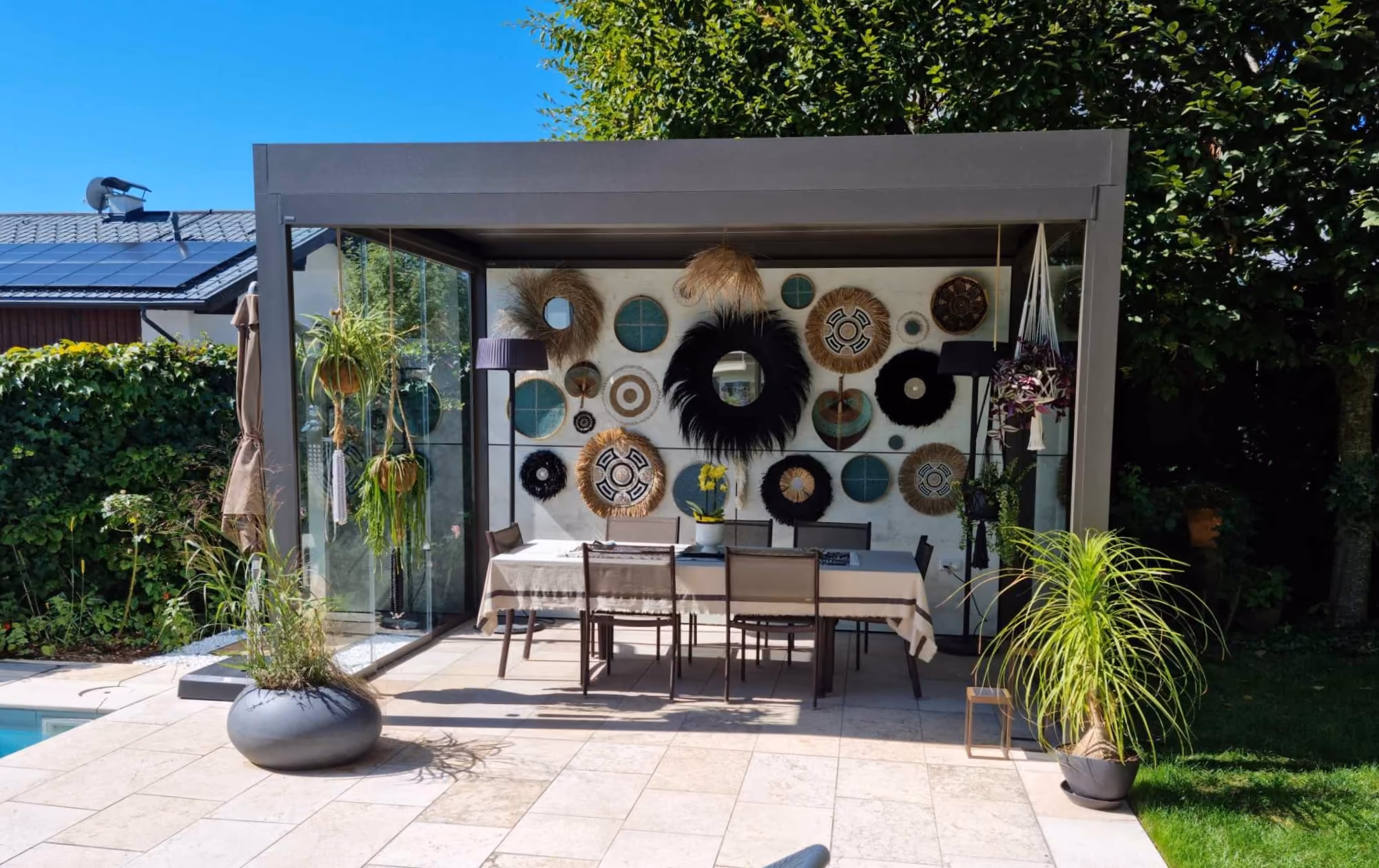 Moderner Gartenpavillon mit Esstisch, sechs Stühlen und vielen dekorativen Wandspiralen.