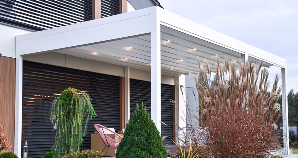 Weißes modernes Terrassendach mit integrierter Beleuchtung an Haus mit Pflanzen.