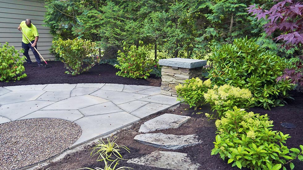 Landscaping and patio installation surrounded by greenery