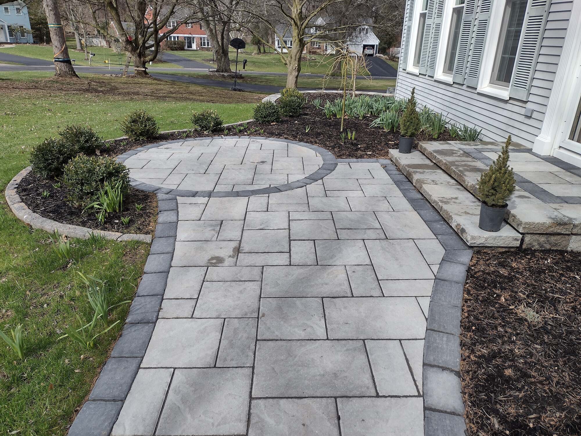 Outdoor space showing hardscaping brick path next to grass and plants in Monroe and Surrounding Counties