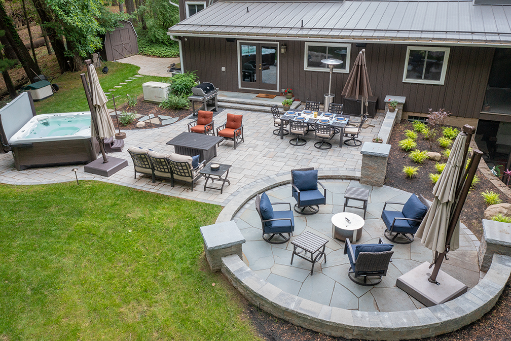 Finalized hardscaping patio project with seating areas, hot tub and a garden.