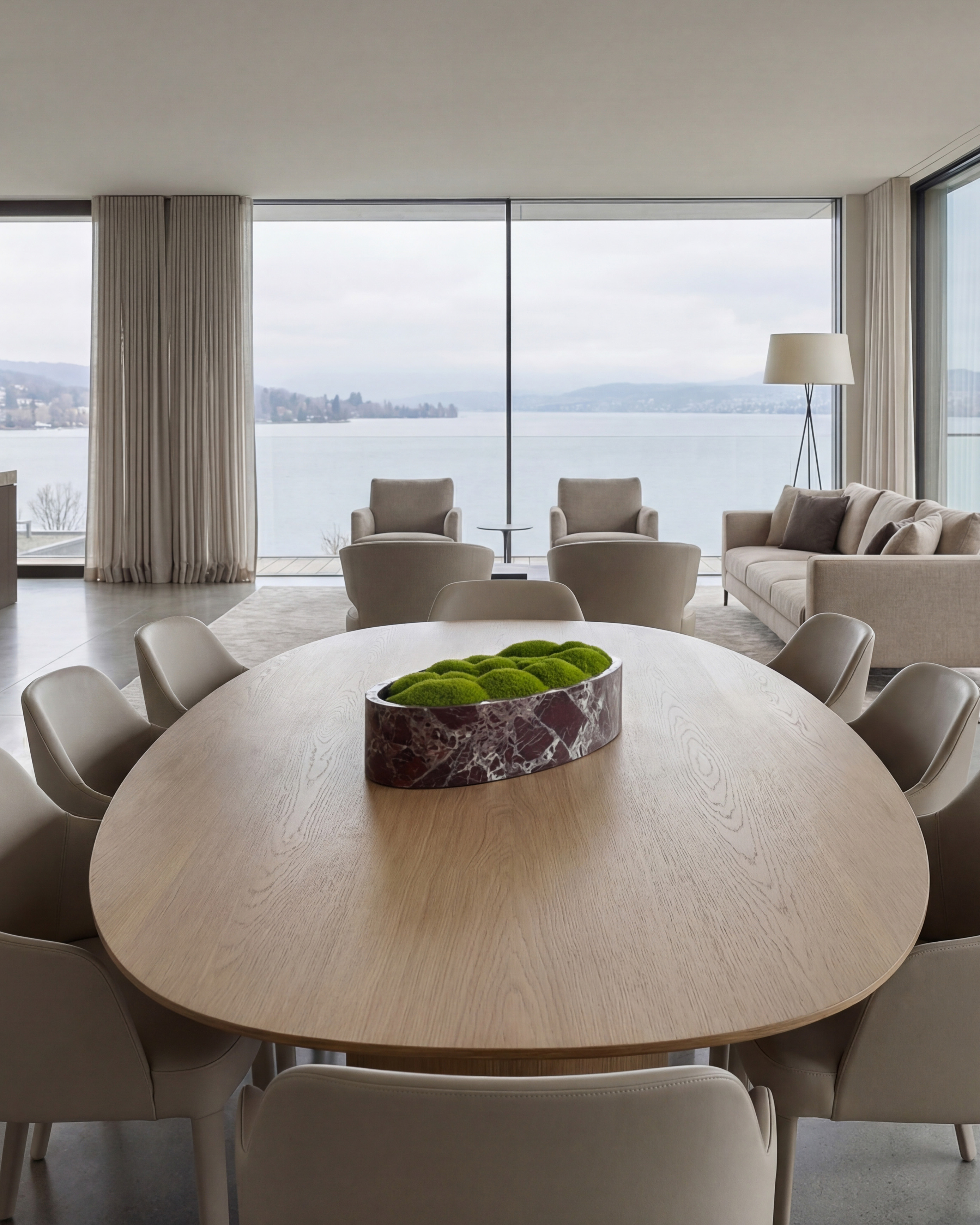 Marmorschale mit grünem Moos auf einem ovalen Esstisch in einem exklusiven Wohnambiente mit Panorama-Seesicht