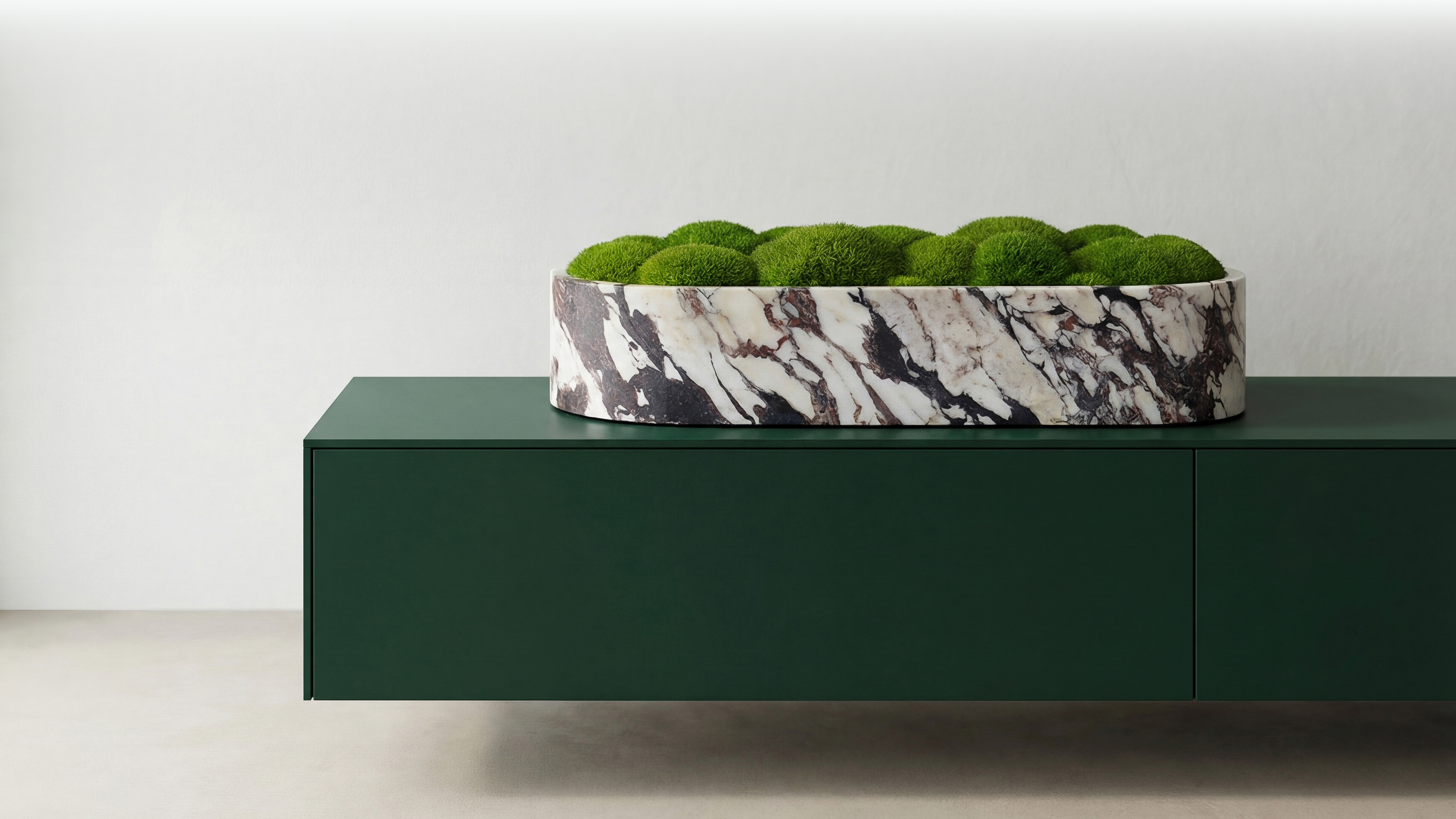 Konserviertes Moos in einer edlen Marmor-Vase auf einem dunkelgrünen Lowboard – Natürliche Wohndekoration