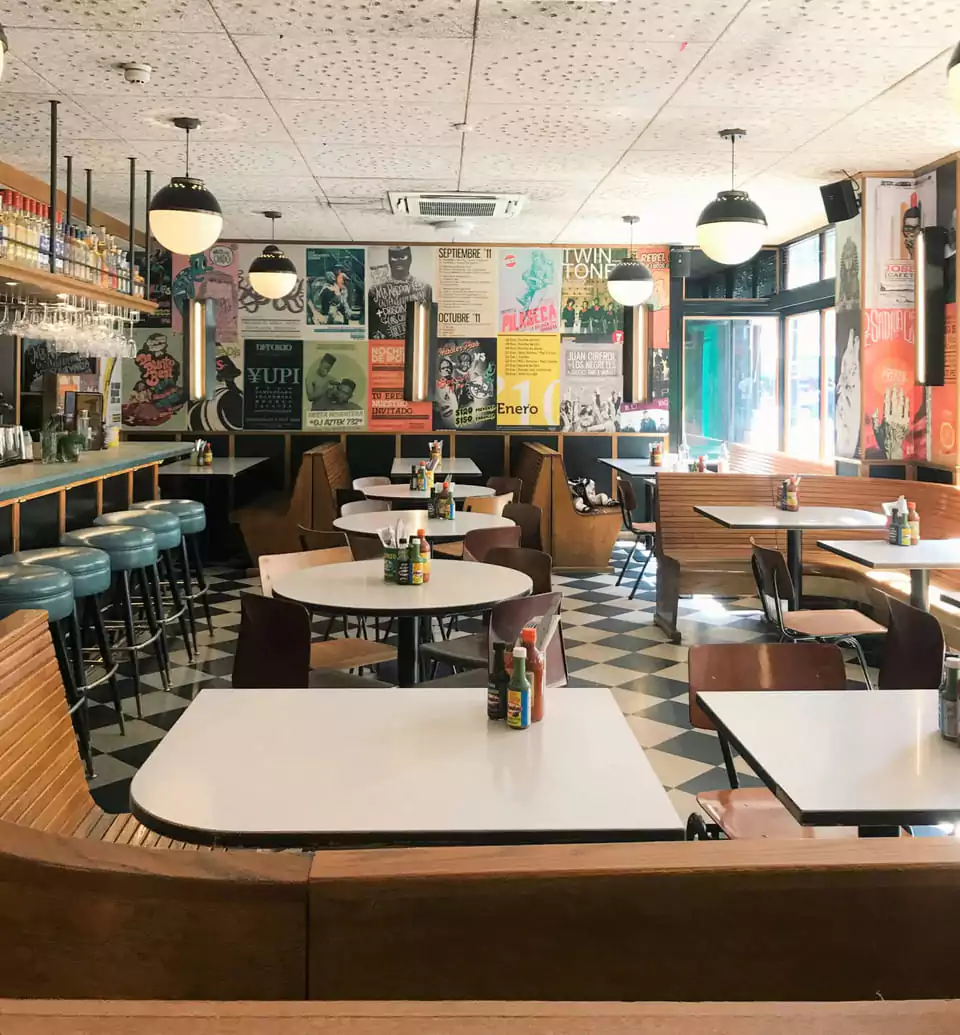 A charming outdoor café in Soho, London, featuring rustic wooden furniture, lush greenery, and a relaxed ambiance—an ideal spot for alfresco dining. Discover Soho’s best hidden gems with Ambl.