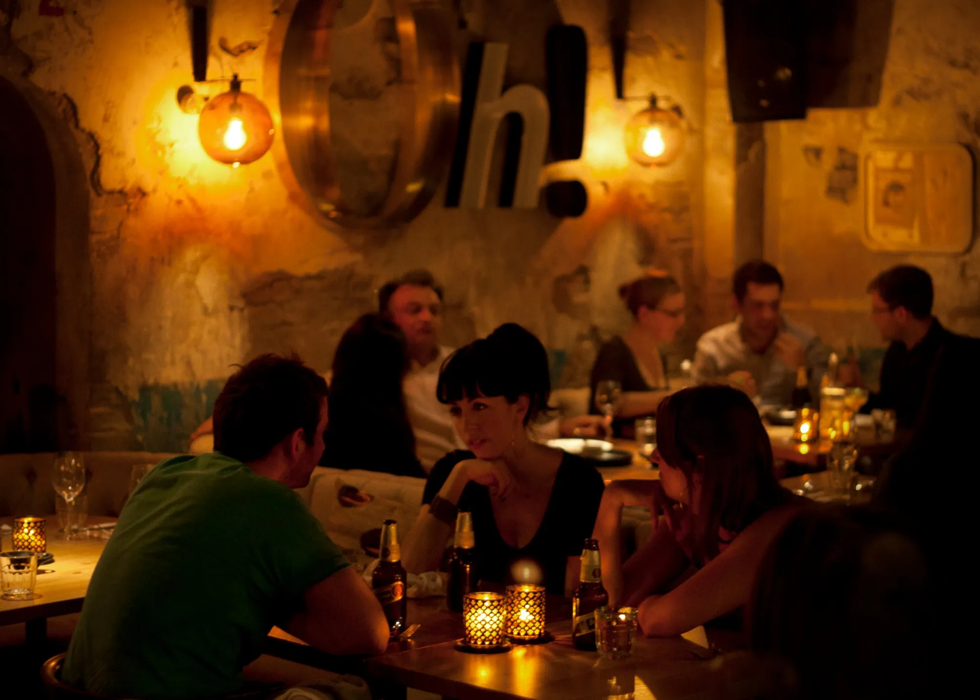 A plate of three soft tacos filled with seasoned meat, fresh greens, diced tomatoes, and shredded cheese, topped with a creamy sauce being drizzled from above. Discover the best spots for mouth-watering Mexican cuisine with Ambl.