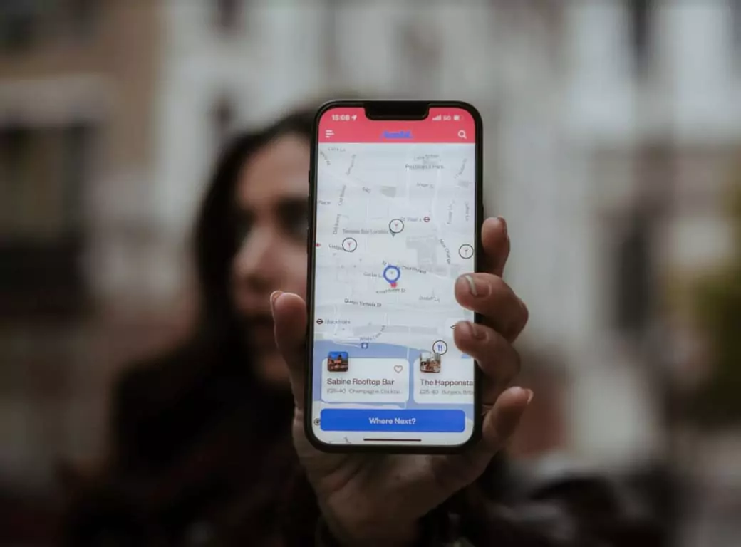 A person holding a smartphone displaying the Ambl app, which helps users discover and book bars, restaurants, and pubs instantly.