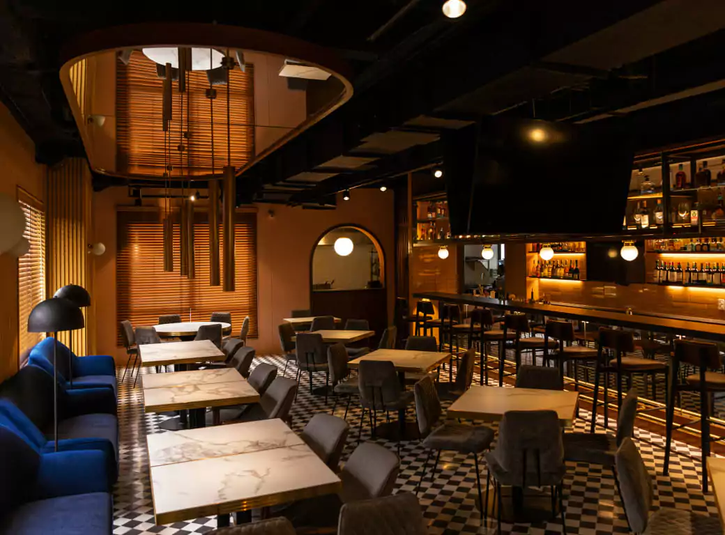 A sleek and stylish bar with contemporary decor, marble tables, and a warm ambiance, representing the trendy spots discoverable via Ambl.