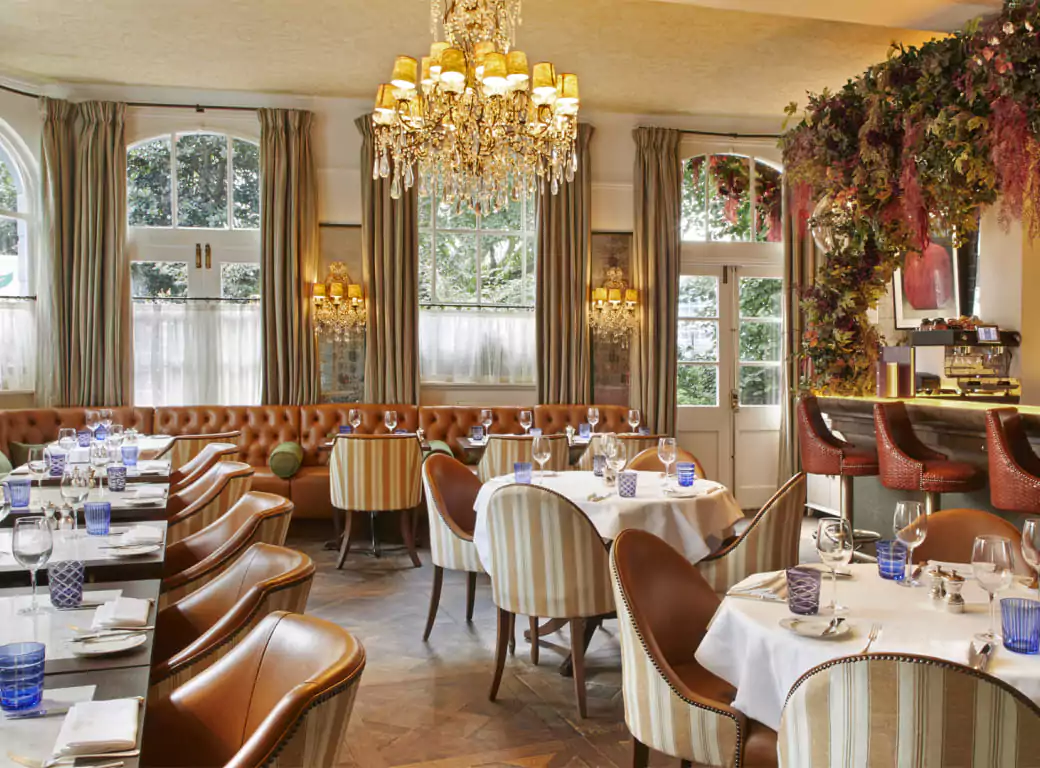 An elegant restaurant with a luxurious chandelier, plush seating, and beautifully set tables, offering a refined dining experience. One of the Ambl-featured venues perfect for a memorable meal in Covent Garden.