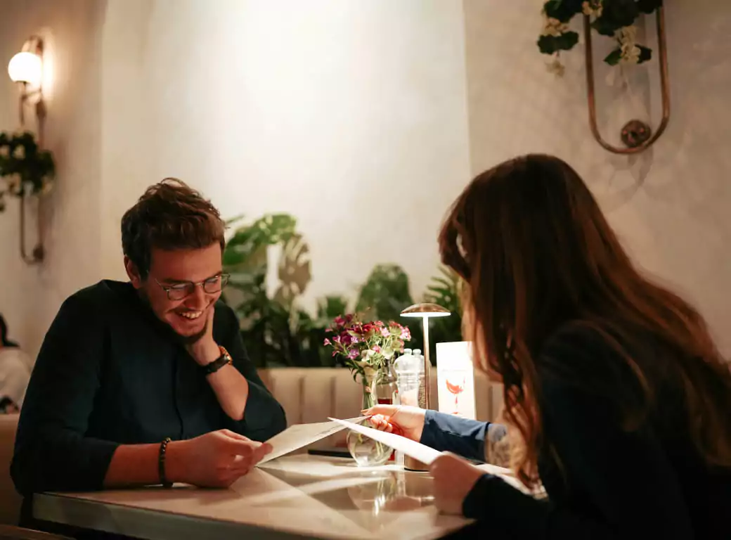 A couple enjoying a cozy, romantic dinner at an intimate restaurant with warm lighting and elegant décor. Discover the best date-night spots in London with Ambl.