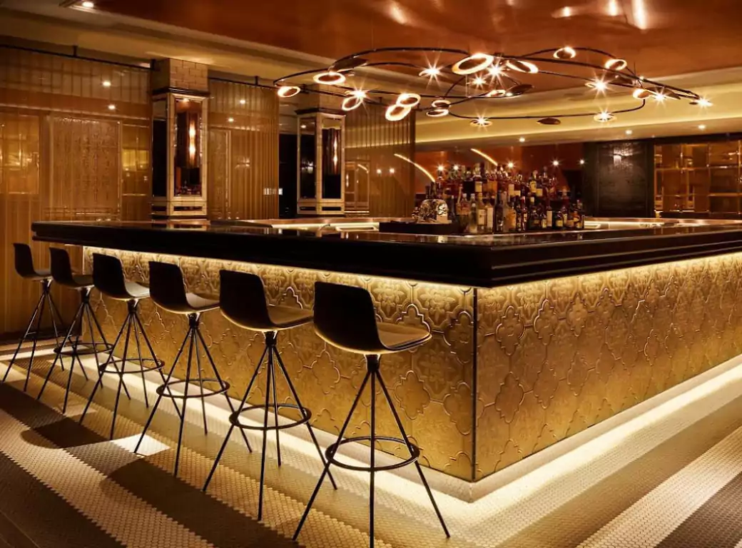 A stylish and luxurious bar with golden accents, modern lighting, and sleek black barstools, creating the perfect ambiance for a night out in London. Discover hidden gems like this with Ambl.