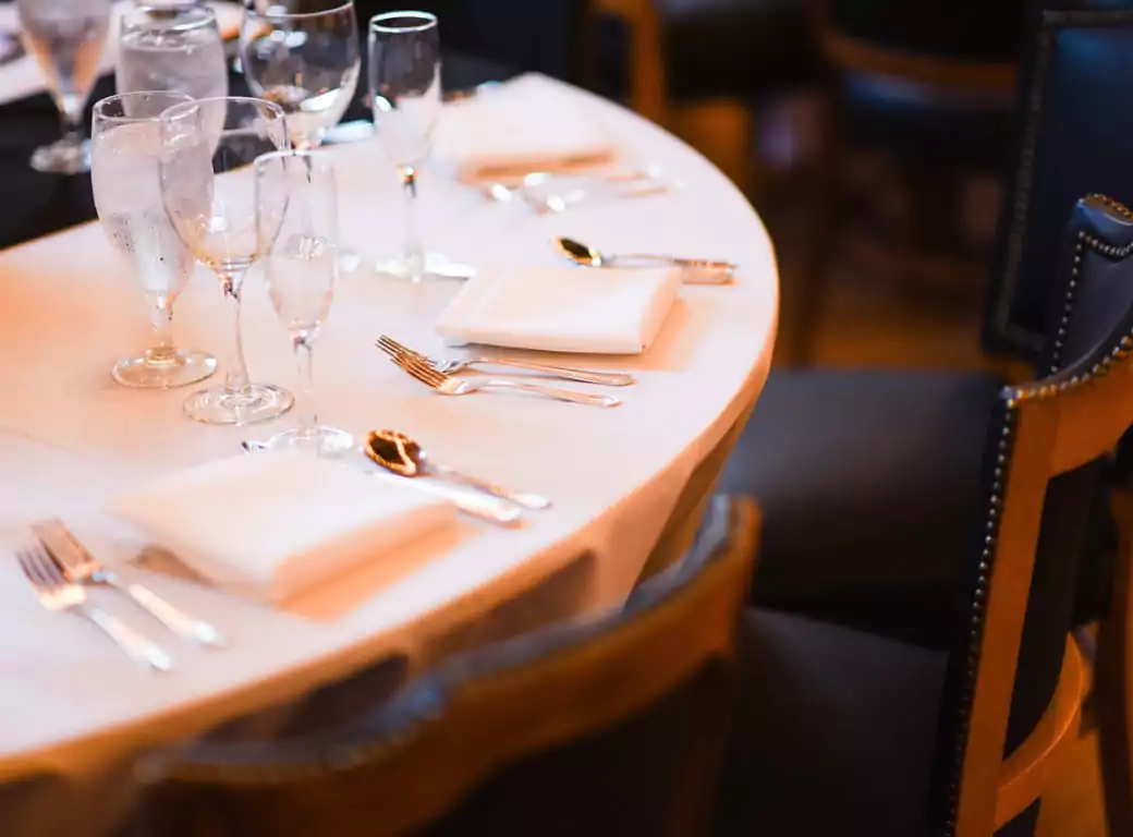 A beautifully set fine dining table with elegant glassware, crisp white tablecloths, and polished silverware, perfect for a luxurious dining experience. Whether for a special occasion, business dinner, or date night, explore the most fancy restaurants with Ambl.