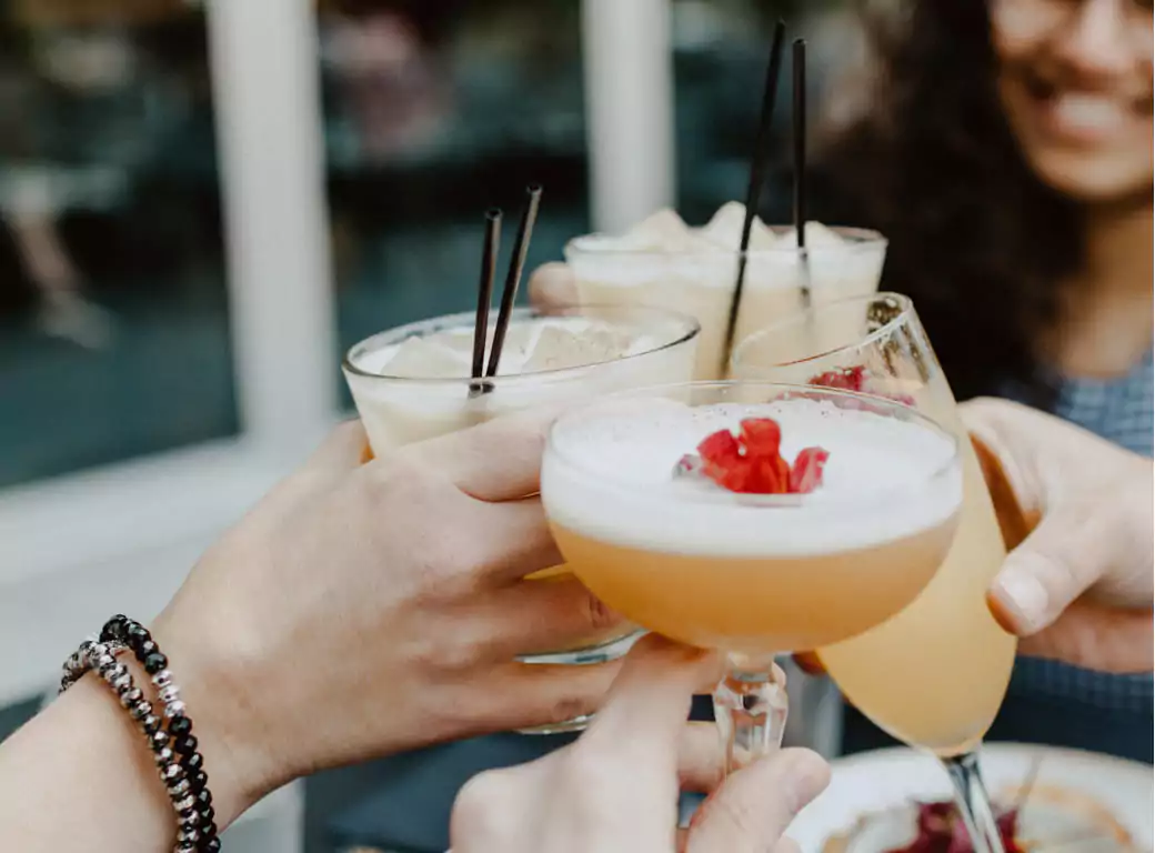A group of friends toasting with delicious brunch cocktails, featuring frothy, garnished drinks and iced beverages. Whether it’s a weekend brunch, bottomless brunch, or a casual meet-up, find the best brunch spots with Ambl.