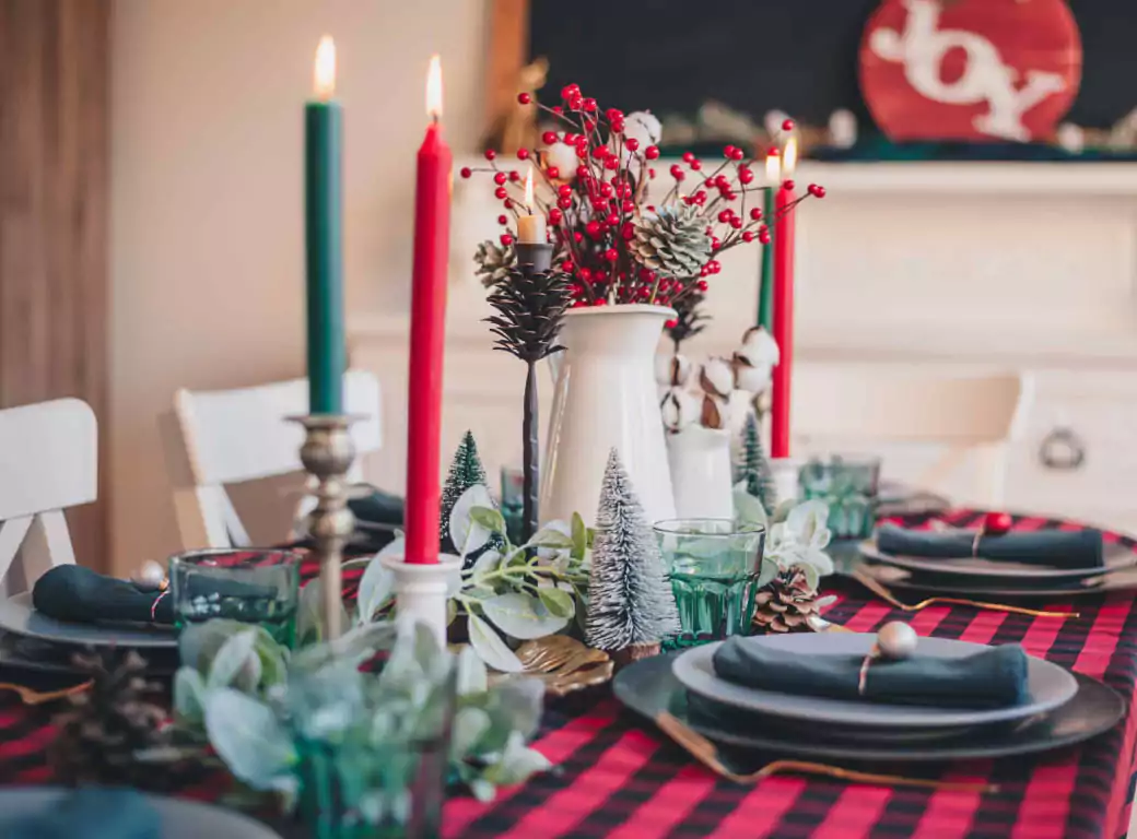 A beautifully decorated Christmas dining table set for a festive meal, featuring red and green candles, pinecones, and holiday decor—perfect for finding a cozy seasonal dining spot with Ambl.