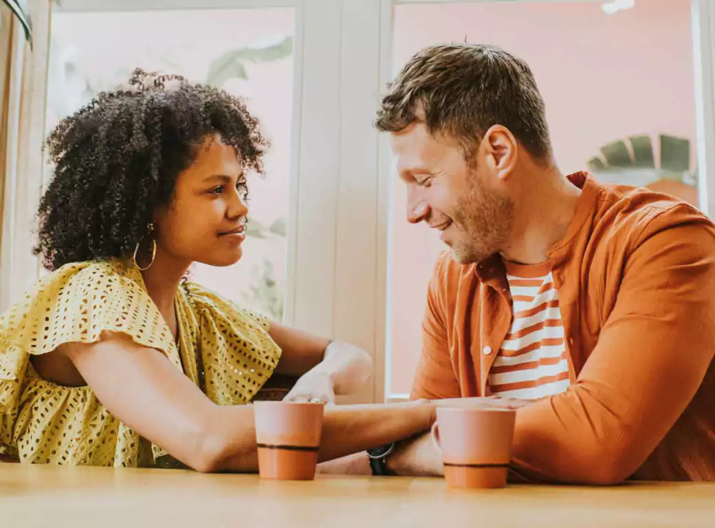 A smiling couple enjoying coffee at a charming café, engaged in warm conversation—an ideal first date setting easily discovered with Ambl.