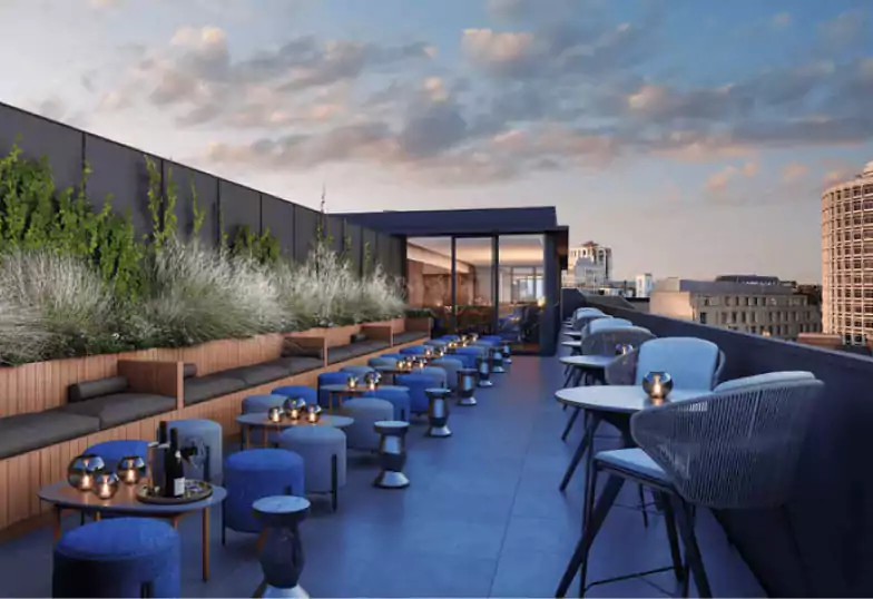 A stunning rooftop bar with elegant outdoor seating, stylish blue decor, and a panoramic view of the city skyline at sunset. Discover London’s best rooftop bars with Ambl.