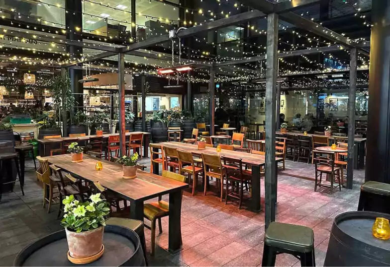 A beautifully designed restaurant with rustic wooden elements, cozy bar seating, and an artistic yellow wall decor. Let Ambl help you discover London’s best dining experiences.