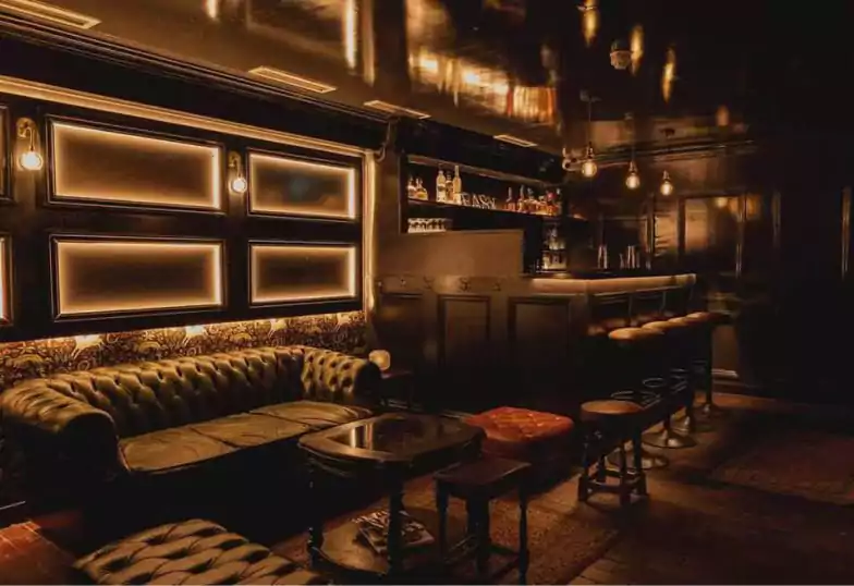 A sleek and intimate cocktail lounge with leather seating, moody lighting, and a cozy, underground vibe, perfect for a night out via Ambl.
