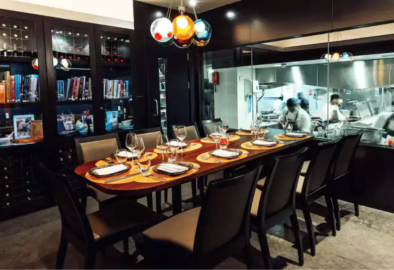 An intimate fine-dining experience at Benares, featuring a sophisticated private dining setup with a view into the bustling kitchen. Find exclusive dining spots like this with Ambl.