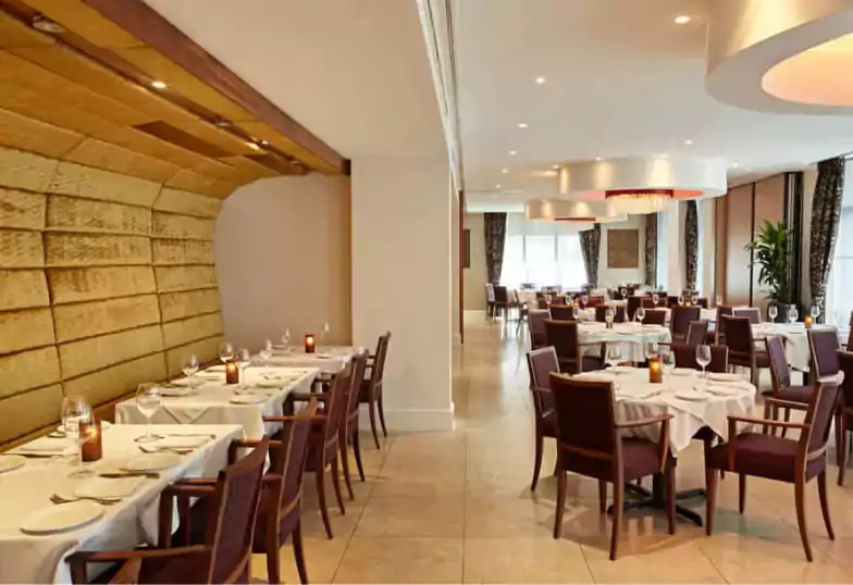 A sophisticated dining space with crisp white table settings, warm lighting, and modern décor at Bombay Palace. Explore top-tier Indian cuisine spots like this with Ambl.