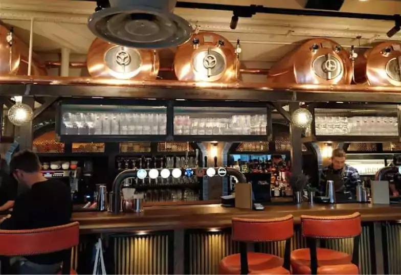 A lively bar with large copper beer tanks, an inviting counter, and an industrial-chic aesthetic at Broadleaf. Find the perfect place for casual drinks with Ambl.