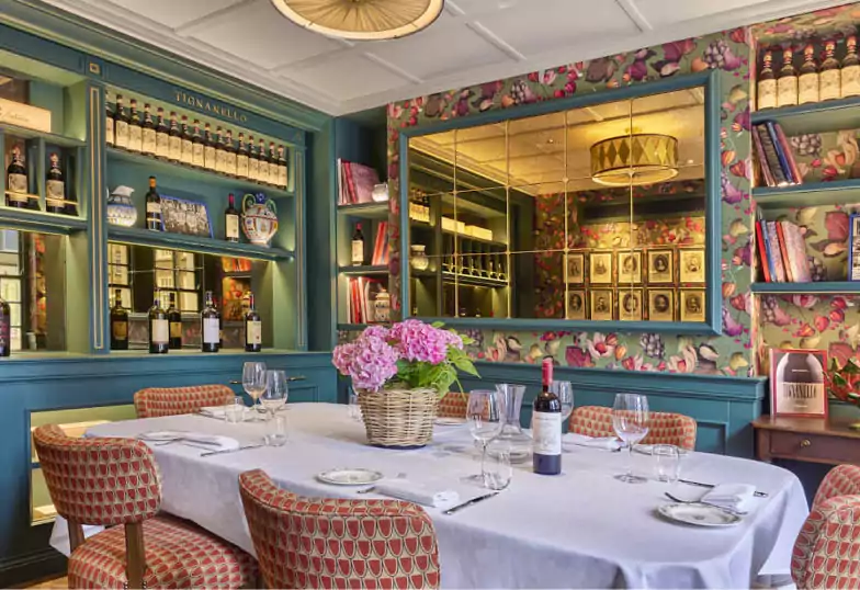 A charming and intimate Italian dining space with floral wallpaper and curated wine selections at Cantinetta. Explore unique restaurants like this with Ambl.