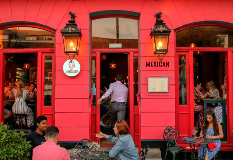 A lively Mexican bar and restaurant with a bold red exterior at Cheeky Chicos. Discover vibrant dining experiences with Ambl.
