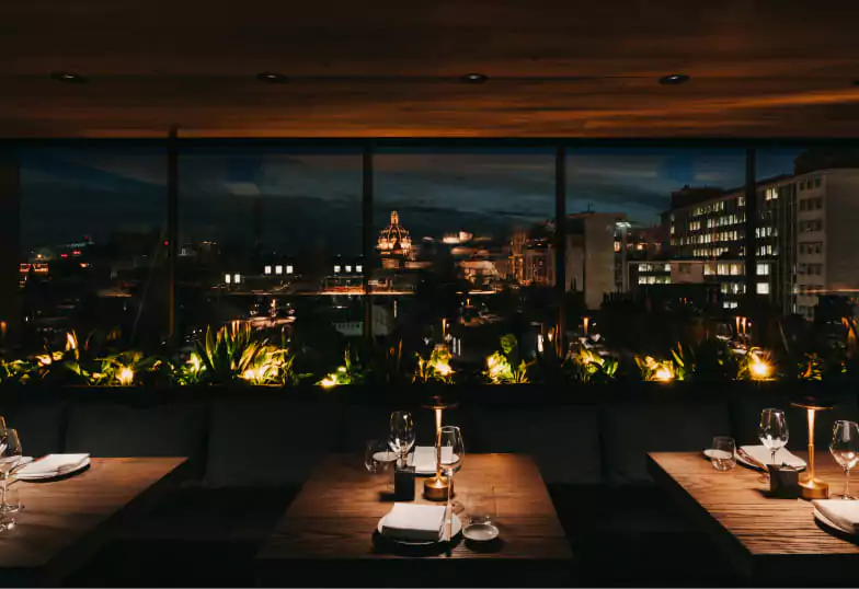 A sleek and modern rooftop restaurant offering a stunning panoramic view of the city skyline, perfect for a memorable night out with Ambl.