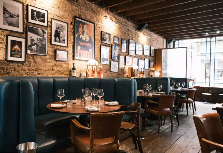 A cozy and stylish restaurant with a warm open fireplace, elegant table settings, and a well-stocked bar, creating the perfect intimate dining experience. One of the hidden gems discoverable through the Ambl app.