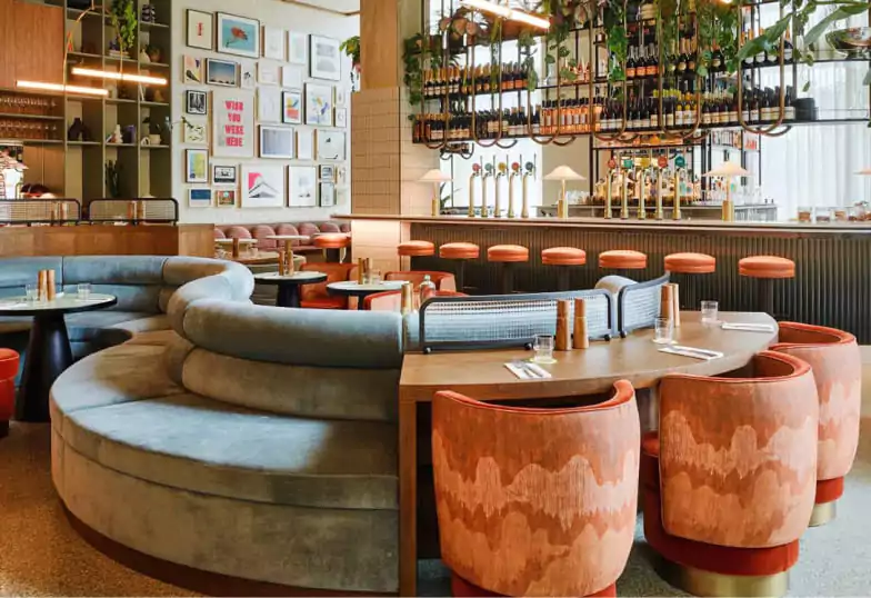 A bright and contemporary dining space with plush curved seating, soft pastel tones, and an inviting bar. A laid-back yet stylish venue perfect for a leisurely meal. Explore more modern eateries on Ambl.