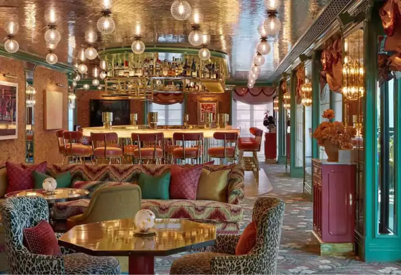 A glamorous cocktail bar with plush lounge seating, mirrored ceilings, and a golden-lit bar, exuding vintage charm and sophistication. A stunning spot for handcrafted cocktails. Explore more elegant bars on Ambl.