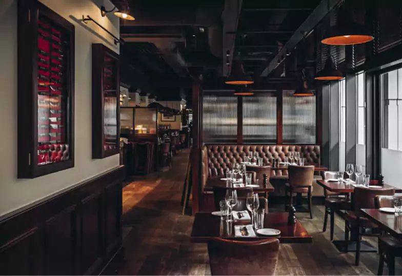 A sophisticated steakhouse with tufted leather booths, rich wooden interiors, and elegant lighting, offering a refined dining experience. Find more upscale restaurants on Ambl.