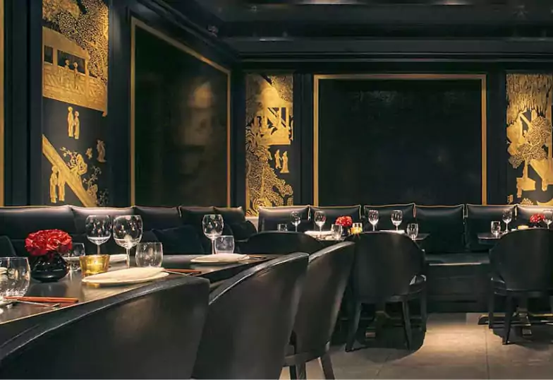 An elegant dining space with dark tones, golden accents, and an intimate atmosphere, ideal for contemporary Chinese cuisine. Find more luxurious dining experiences on Ambl.