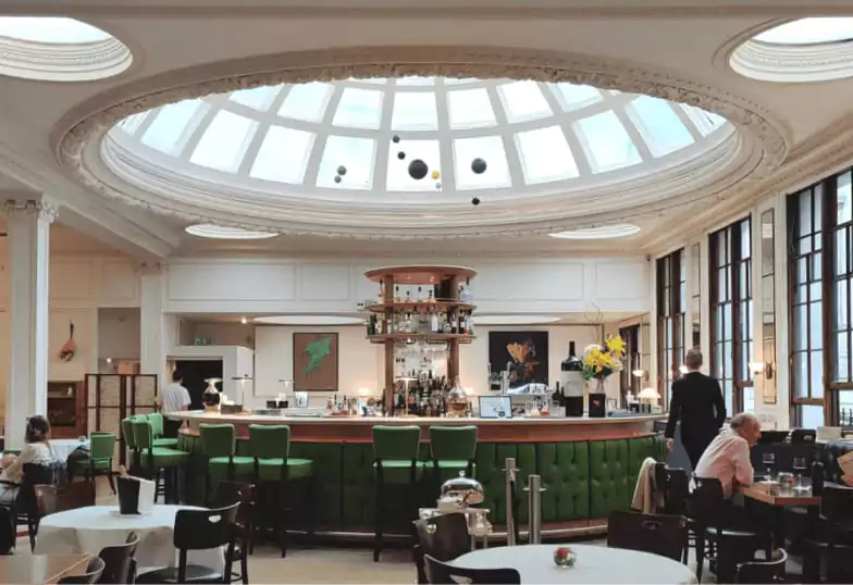 A beautifully plated brunch spread, featuring dishes like fried eggs with crispy fried chicken, avocado toast with poached eggs, a full English breakfast, and a savory stack with hollandaise. Accompanied by a vibrant berry cocktail, this setup is perfect for a business breakfast or weekend brunch. Discover top breakfast spots with Ambl.