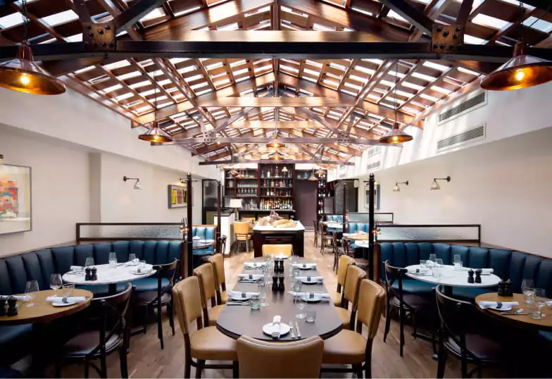 A sophisticated Italian dining experience at Café Murano, with a glass-paneled ceiling, elegant seating, and a well-stocked bar. Explore elegant restaurants with Ambl.