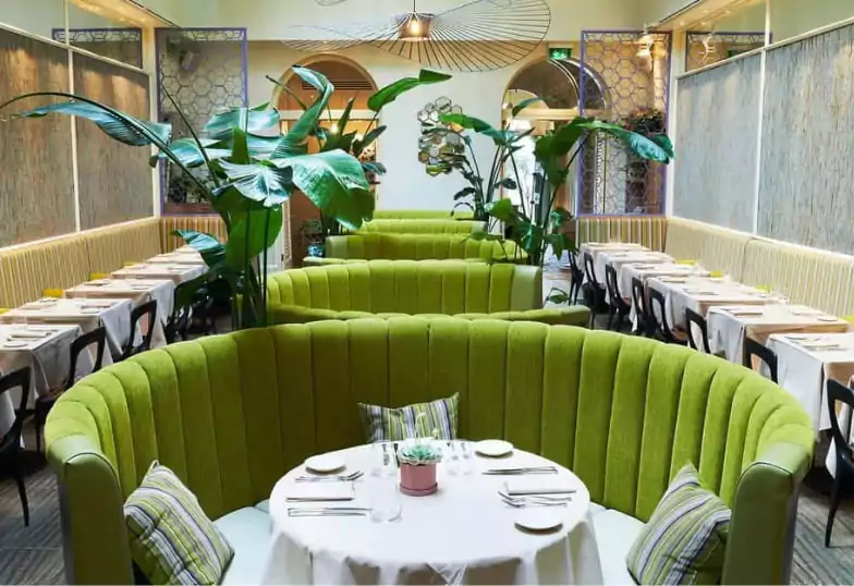 A stylish Provençal restaurant with lush greenery, plush seating, and elegant decor at Cigalon. Find hidden gems like this with Ambl.