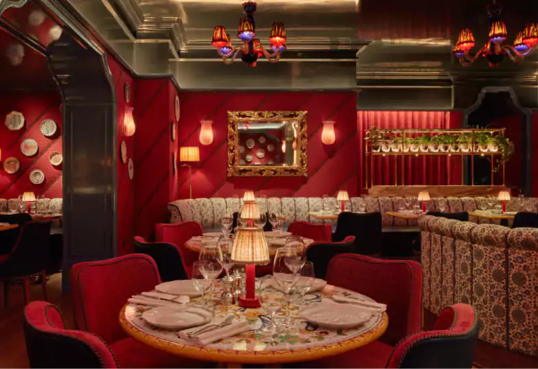 A richly decorated restaurant with deep red tones, patterned sofas, and intimate lighting, creating a luxurious and elegant dining experience with Ambl.