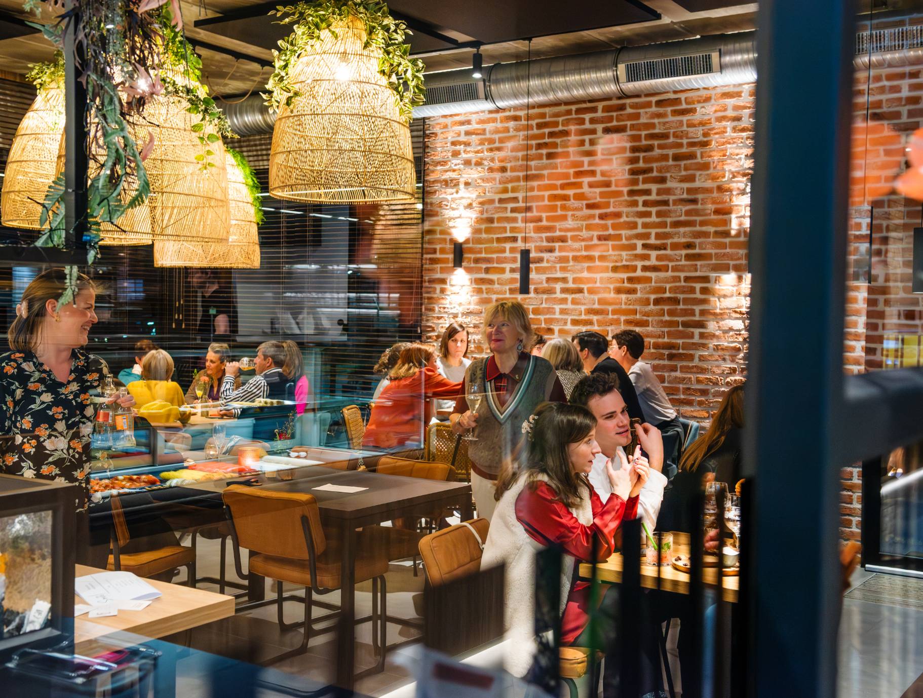 Gezellig restaurant met mensen die genieten van een diner, omringd door sfeervolle verlichting en groene decoraties.