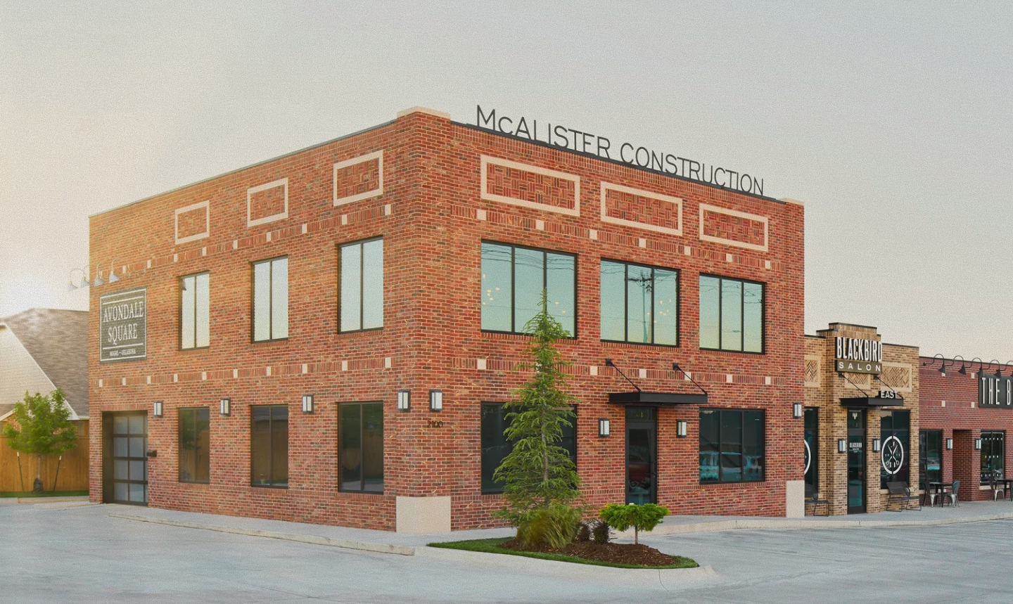 Two-story brick building with signs for McAlister Construction and Avondale Square, next to a Blackbird Salon storefront.