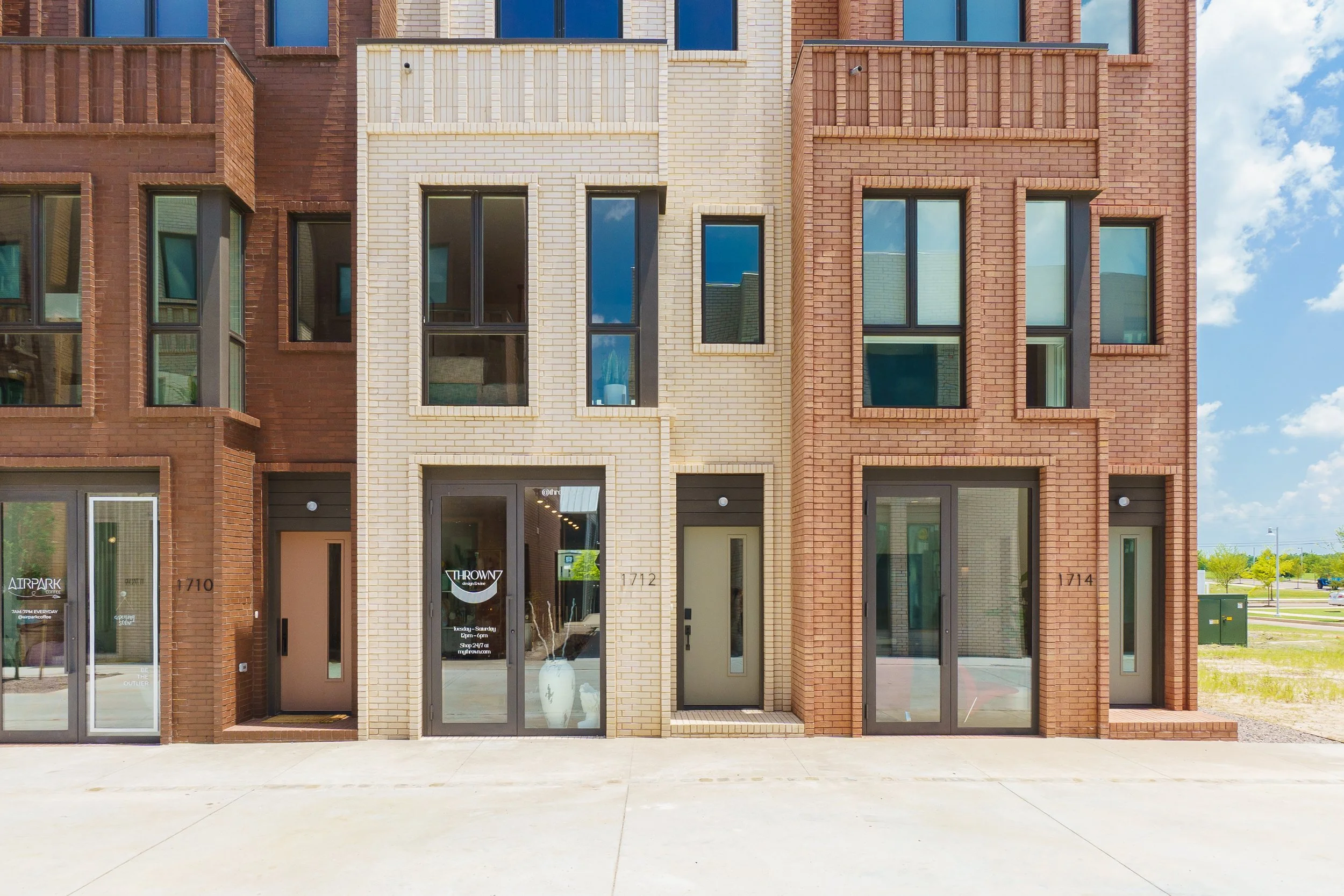 Modern row of townhomes with mixed dark and light brick exteriors and large windows under a blue sky.
