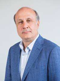 Middle-aged man in blue checkered blazer and white shirt against a plain light background.