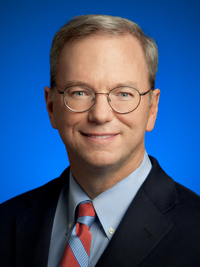 Smiling man wearing glasses, suit jacket, blue shirt, and striped tie with blue background.