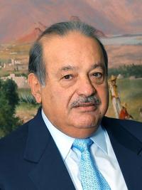 Older man with a mustache wearing a navy suit and light blue tie with a scenic mountain background.