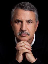 Middle-aged man with salt-and-pepper hair and mustache resting chin on clasped hands.