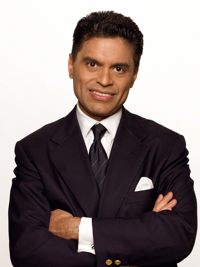 Man in dark suit and tie with arms crossed smiling against white background.