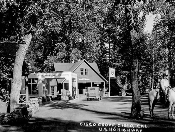 Black and white historical photo of a small gas station and store labeled Standard Oil Products in Cisco Grove, California, with an old car and a person on horseback nearby.