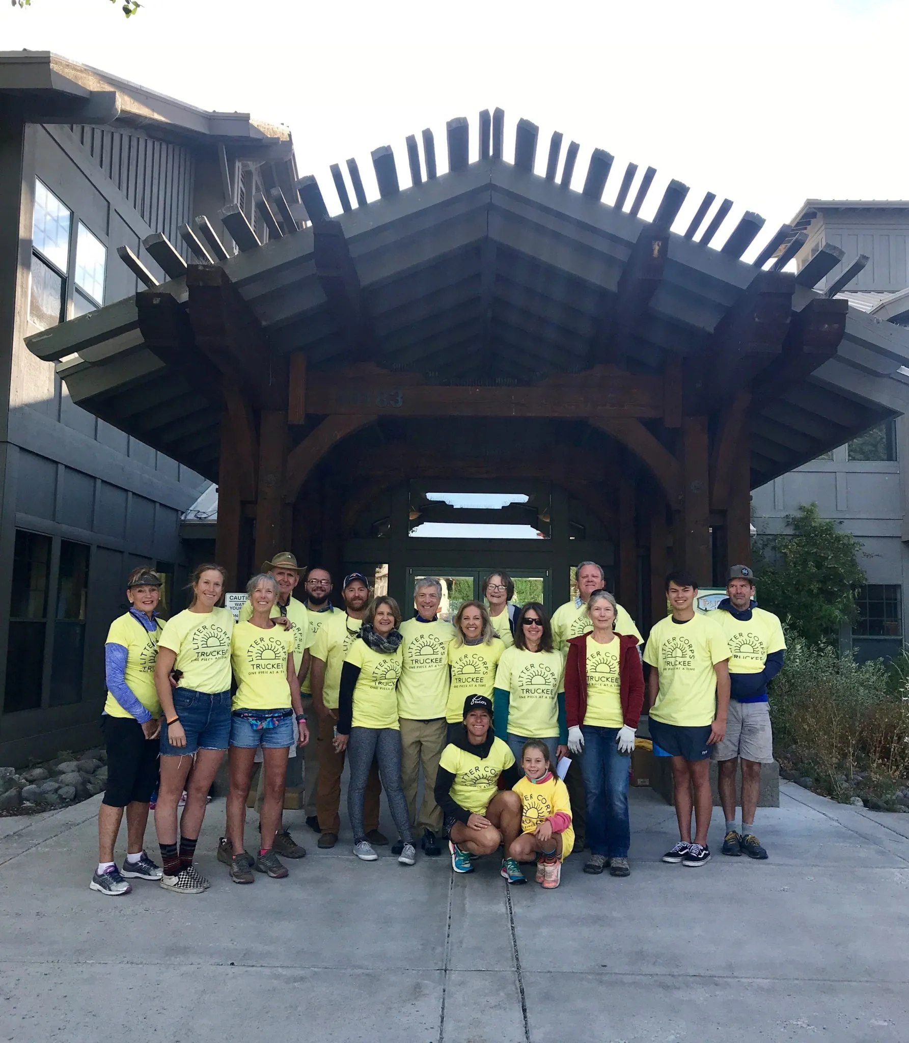 Large crowd of people gathered at an outdoor festival with tents, flags, and a mountainous background under a clear sky.