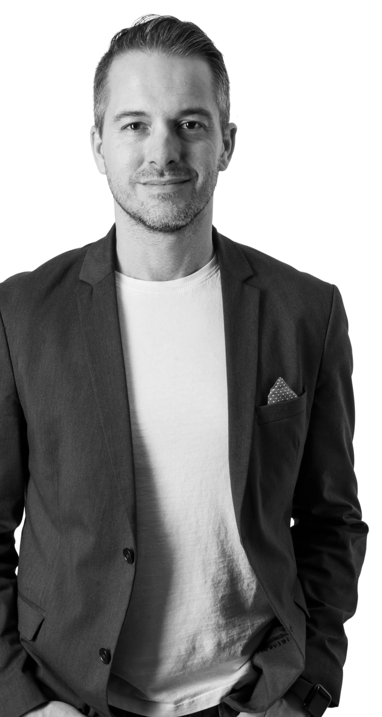 Smiling man with short hair wearing a blazer over a white t-shirt.