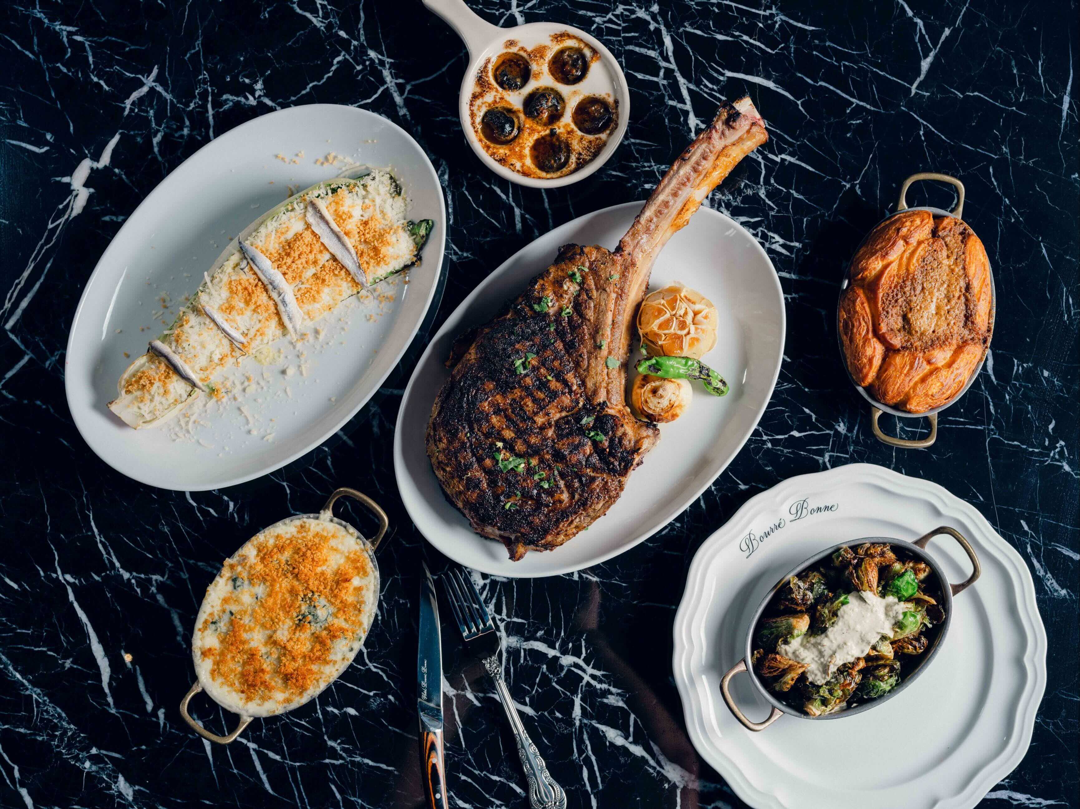 A table topped with white plates filled with food.