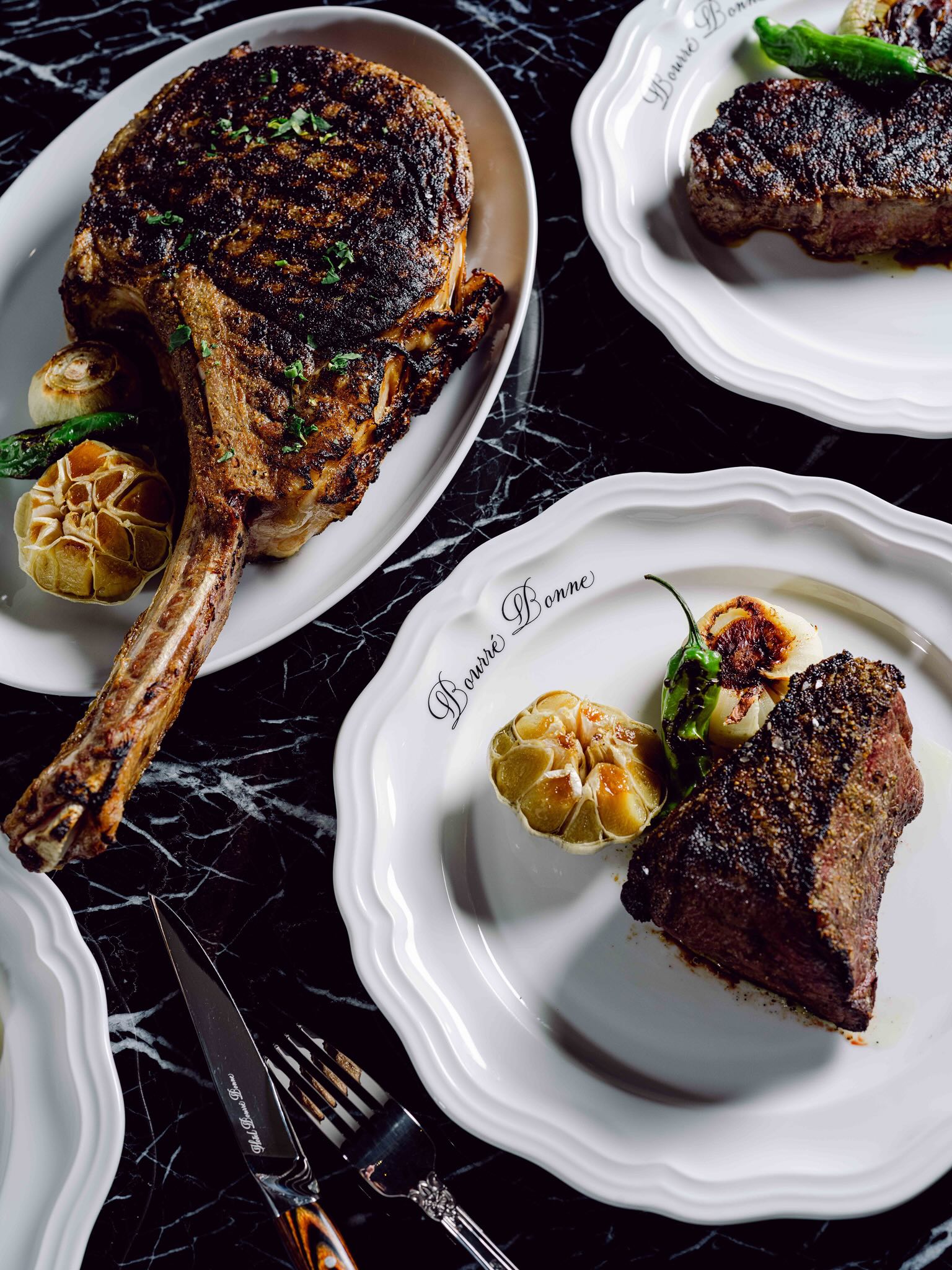 A table topped with white plates filled with food.